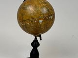an old globe on a black stand with a white background