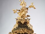 a gold clock with a bird on top of it