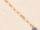 a gold chain bracelet with a blue stone on it