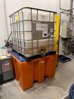 un grand conteneur posé sur une palette dans une pièce