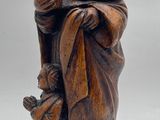 wooden figurine of a monk holding a child and a bird