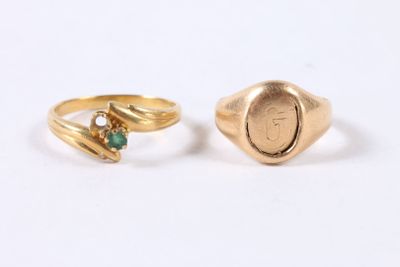 two gold rings with emerald stones on them on a white surface
