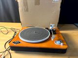 un tourne-disque posé sur une table en bois, à côté d'un carton