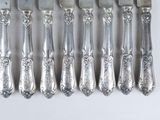 six forks and a knife on a white table