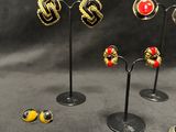 five pairs of earrings on display on a stand