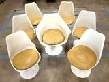 several white chairs with yellow cushions sit in a circle