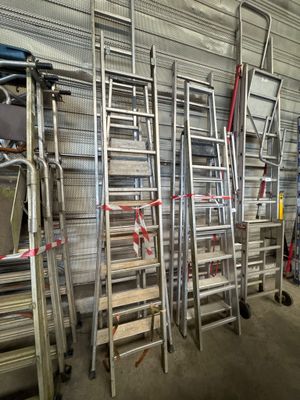 several ladders are lined up against a wall in a warehouse