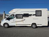 un camping-car blanc garé dans la rue devant un immeuble