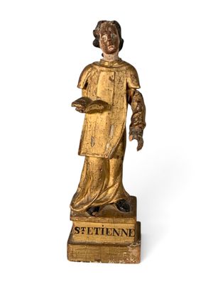 an antique wooden statue of a woman holding a book