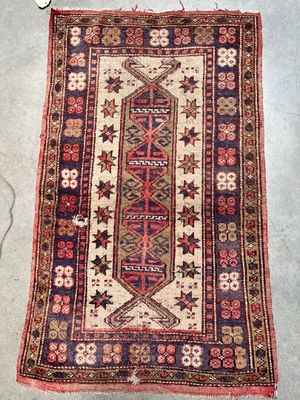 Un vieux tapis est posé par terre à côté d'une paire de ciseaux.