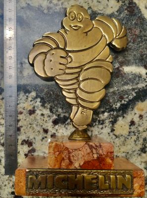 une statue en or représentant un homme tenant un bébé dans ses bras, posée sur un socle en marbre