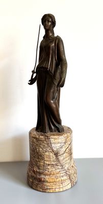une statue représentant une femme tenant une épée, posée sur un socle