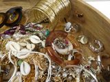 a wooden bowl filled with lots of jewelry and a pair of scissors