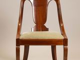 le dossier d'une chaise en bois sur laquelle est posé un coussin vert