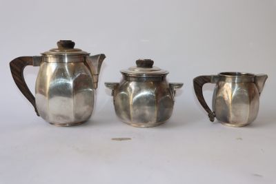 trois théières en argent et une cafetière sur une table