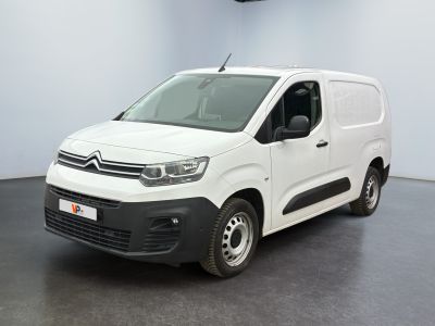 La camionnette blanche est garée dans une pièce au sol noir.