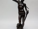 an antique bronze statue of a man holding a sword and a shield