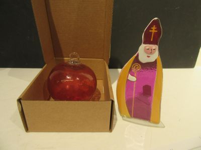 une décoration rouge dans une boîte en carton, à côté d'une autre décoration rouge