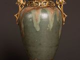 a green vase with gold accents on a wooden table