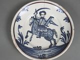 a blue and white plate with a picture of a man riding a horse