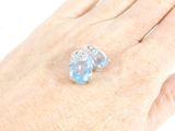 an image of a woman ' s hand holding a ring with a blue topaz stone