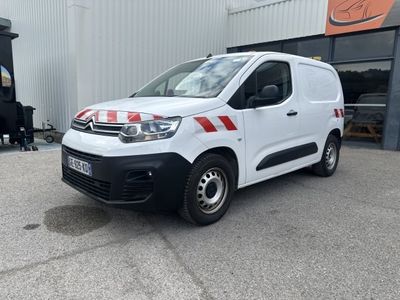 La camionnette blanche est garée devant un immeuble orné d'une bande rouge et blanche.