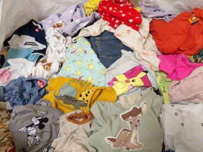 a large pile of baby clothes in a bin on the floor