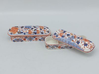 deux petites boîtes ornées de motifs floraux, posées sur une surface blanche