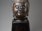 une tête de Bouddha sculptée posée sur un socle en bois