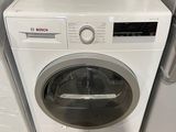 un micro-ondes posé sur une machine à laver, à côté d'un sèche-linge