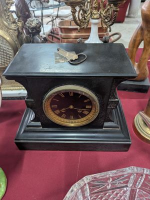 une horloge noire posée sur une table recouverte d'une nappe rouge
