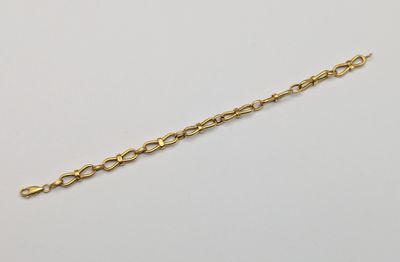 a gold plated bracelet with a chain that has been set on a white surface