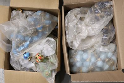 deux boîtes remplies de décorations bleues et blanches posées par terre