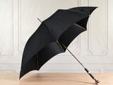 an open black umbrella sitting on top of a wooden floor