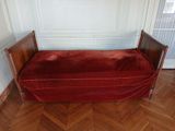 un lit recouvert d'une couverture rouge, dans un coin de la pièce
