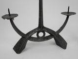 an iron candle holder with two candles on top of it