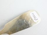 une cuillère en argent portant un numéro, posée sur une surface blanche