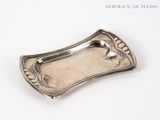 a silver plate with a bird on it on a white surface