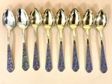 six cuillères en argent ornées de motifs bleus et dorés sont alignées en rangée