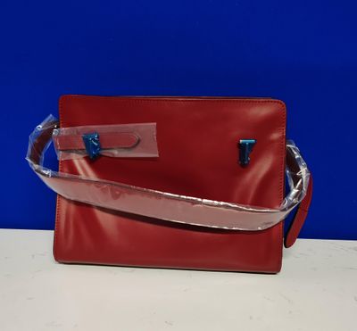 un sac à main rouge avec une bandoulière argentée et une poignée bleue