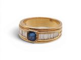 a close up of a gold ring with a blue sapphire and baguets