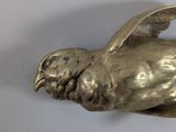 a silver bird that is sitting on a white surface