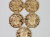 quatre pièces d'or ornées d'un blason, posées sur une surface blanche