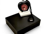 une horloge en forme de cœur posée sur un coffret noir, avec un porte-clés