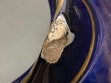 a close up of a blue vase with a gold decoration on it