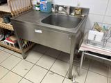 a stainless steel sink in a kitchen with a wire basket on the floor