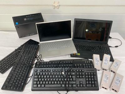 several laptops, keyboards, mouses, and other electronic devices are on a table