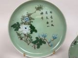 a green plate with flowers on it next to a vase