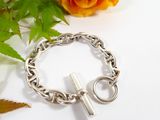 a silver bracelet with a cross on it next to a rose