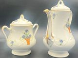 two pieces of porcelain teapots with flowers on them sitting on a table